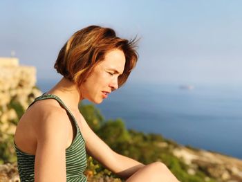 Side view of young woman against sea