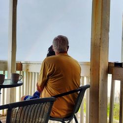 Rear view of man standing by railing against sky