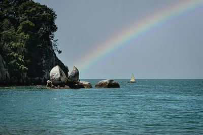 Scenic view of rainbow over sea against sky