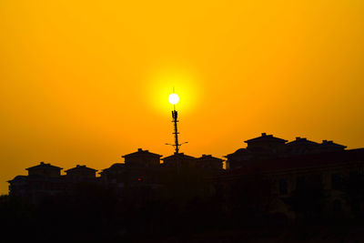 Low angle view of buildings against orange sky