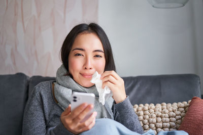 Portrait of young woman sitting on sofa at home