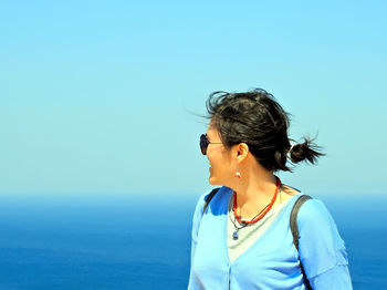 Beautiful woman against sea against clear blue sky