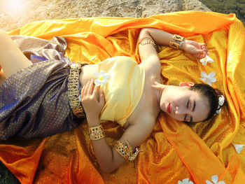 High angle view of woman lying on yellow fabric