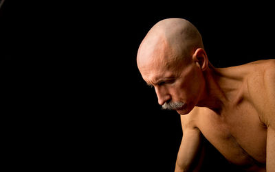 Mature man with shaved head against black background