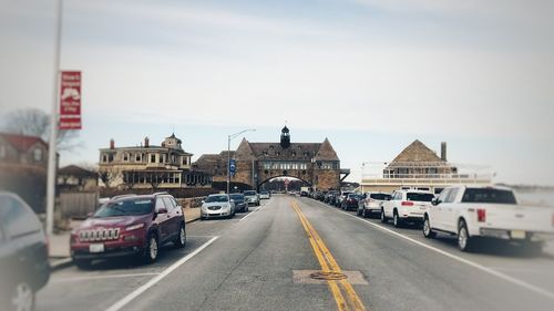 Cars on street in city against sky