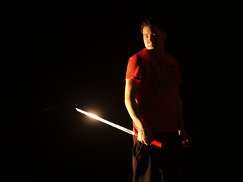 Samurai standing with shining katana against black background