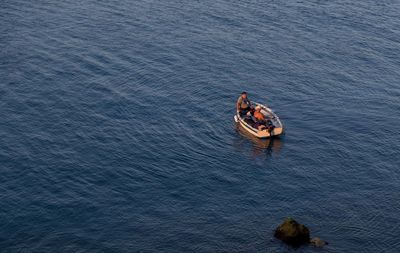 High angle view of men fishing while sitting in motorboat