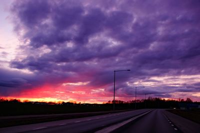 Scenic view of landscape against cloudy sky at sunset