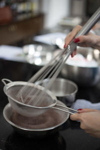 Cropped image of woman using wire whisk while baking in kitchen