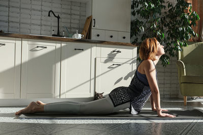 Middle aged woman practicing meditation at home, lady in yoga pose doing yoga for mental balance 