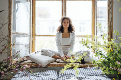 Portrait of smiling young woman sitting by window