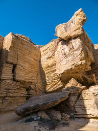 Low angle view of rocks on rock against blue sky