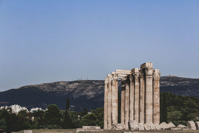 Greek temple ruins on mountain against blue sky