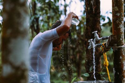 Young man bathing against tree