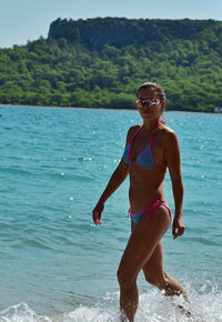 Portrait of woman walking in sea against sky