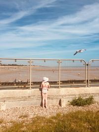 Rear view of girl looking at sea while standing by railing