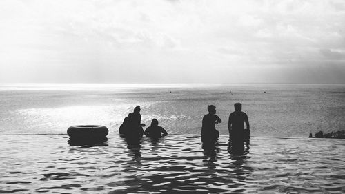 Rear view of silhouette people on beach against sky