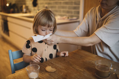 Mother cleaning daughter's mouth with tissue