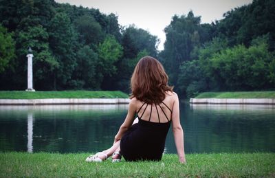 Rear view of woman looking at lake against trees