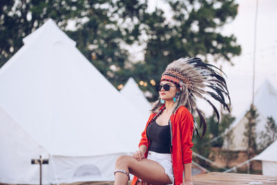 Young woman wearing headdress while sitting on picnic table