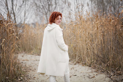 Attractive stylish woman holding dry reed walking in park