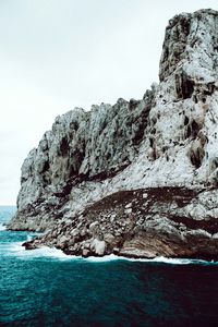 Rock formations by sea against clear sky