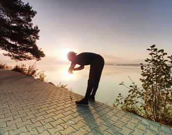 Silhouette man standing by tree against sky during sunset