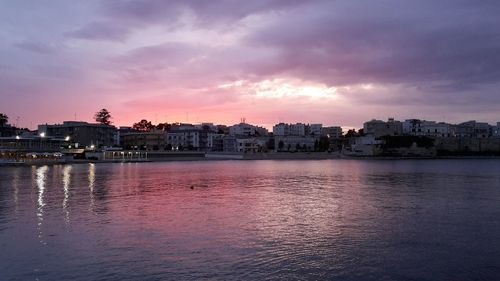 City at waterfront against cloudy sky