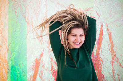 Portrait of smiling young woman standing against graffiti wall