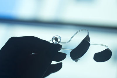 Close-up of hand holding glass with eyeglasses on table