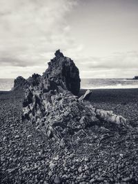 Rock formation on beach against sky