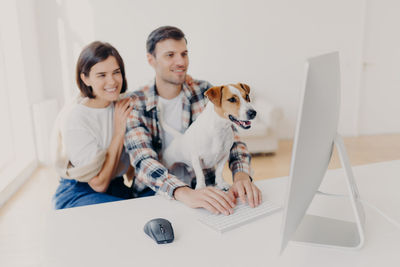 Couple sitting with dog using computer at home