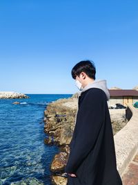 Young man looking at sea against clear sky