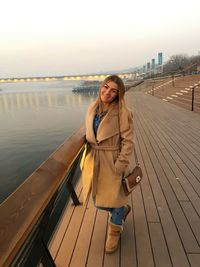 Portrait of young woman standing on promenade against clear sky