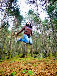 Low angle view of woman against trees in forest