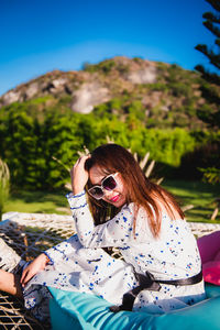 Woman wearing sunglasses sitting on mountain