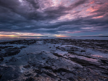 Scenic view of sea against dramatic sky during sunset