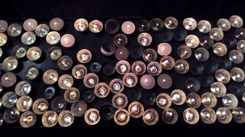 High angle view of lit tea light candles over black background