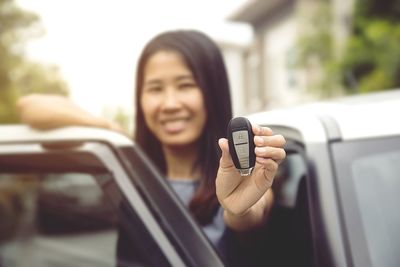 Portrait of smiling man holding camera while sitting in car