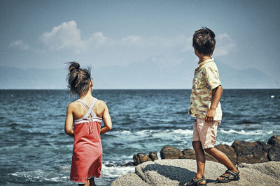 Siblings at beach against sky