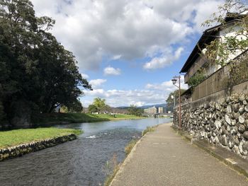 Road by canal amidst buildings against sky