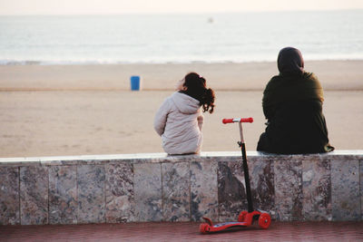 Rear view of couple sitting on beach