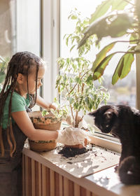 Side view of girl with cat by window