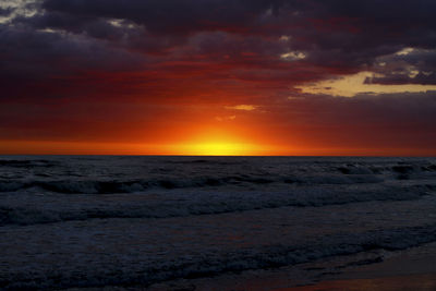 Scenic view of sea against dramatic sky during sunset