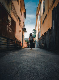 Low angle view of woman on street amidst buildings in city
