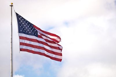 Low angle view of american flag against cloudy sky