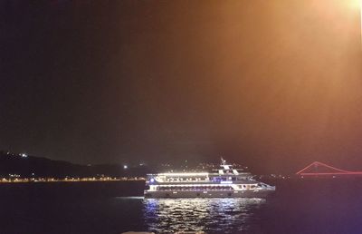 Illuminated ship sailing in sea against sky at night