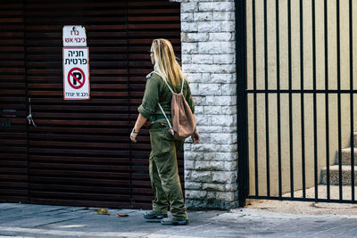 Side view of woman standing against wall