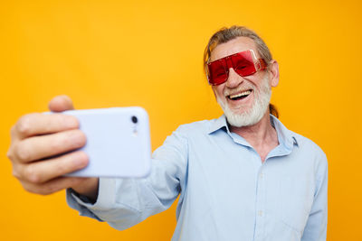 Senior man using smart phone in front of wall