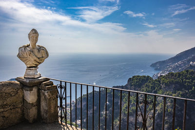 Statue by sea against sky